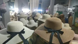 Factory warehouse wholesale display of summer women flat top straw sun hats with black ribbons.