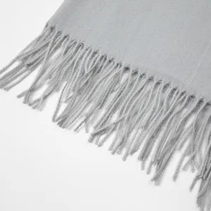 Close-up detail of soft grey winter scarf tassel design, cozy fabric texture display.