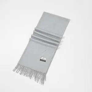 Close-up detail of the soft light gray cashmere-like winter scarf featuring delicate fringe edge.