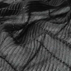 Black pleated fashion scarf fabric detail close up with shimmering silver thread grid design.