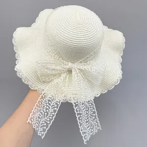 Close-up detail view of women's white summer straw hat featuring delicate lace bow and brim.