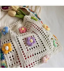 Detailed view of the hand-knitted crochet fabric and colorful floral decorations on the bag