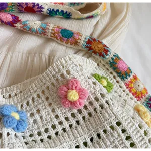 Close-up detail of a handmade crochet shoulder bag featuring colorful knit flowers