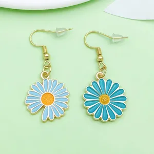 Gros plan détaillé de boucles d'oreilles en alliage émaillé marguerite bleue avec crochets dorés.