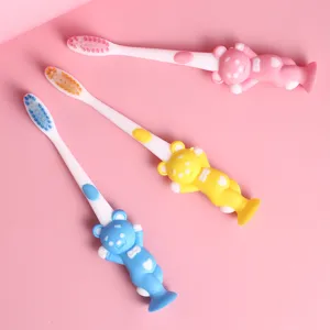 Cute cartoon bear children soft toothbrush with suction cup base and small head design.