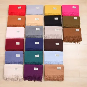 Detailed view showcasing multiple solid color winter tassel scarves in assorted shades.
