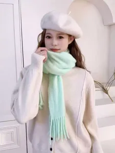 Detailed shot of a soft mint green fuzzy tassel knit scarf worn with a chic sweater and beret.