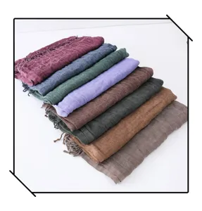 Closeup detail of stacked colorful wrinkled cotton linen scarves with tassels for autumn.