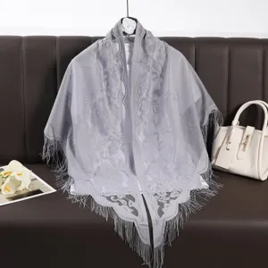 Detail view of grey lace triangular shawl with delicate fringe, hollow-out breathable design.