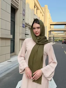 Detailed view of the elegant olive green slub long scarf and beige dress outfit for outdoor wear.