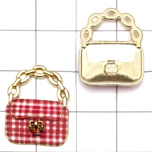 Primo piano di ciondolo borsa in lega color oro accessorio gioielli DIY con smalto a quadri rossi.