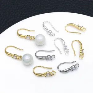 Primo piano di monachelle per orecchini fai da te con zircone e perle, oro e argento.
