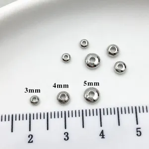 Close up detail of silver spacer beads showing different sizes with ruler reference.