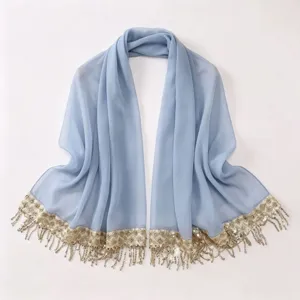 Close-up of light blue chiffon scarf with gold sequin embroidery and delicate tassels.