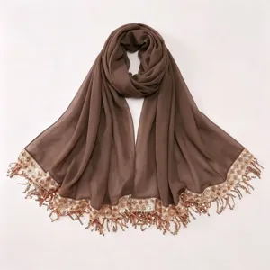 Detail view of the brown chiffon hijab scarf featuring elegant sequined tassel edges and soft fabric.