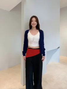 Detalle del look coreano por capas con top de encaje blanco, cárdigan azul y falda roja.