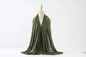 Vue détaillée d'un long foulard uni vert foncé au toucher lin drapé avec élégance.