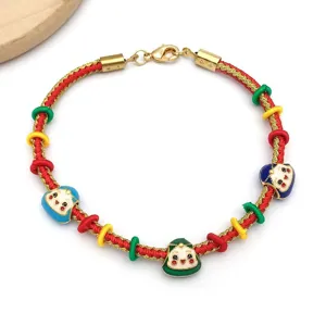 Pulsera de cordón trenzado rojo con hilo dorado, cierre de acero inoxidable y dijes de esmalte.