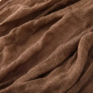 Brown cotton linen crinkled texture fabric detail shot, soft and stylish scarf material.