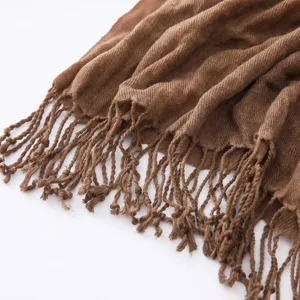 Detail shot of brown textured cotton linen scarf with tassel fringe, casual autumn winter accessory.