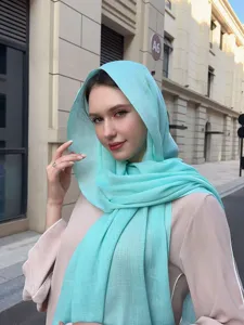 Close-up of a lightweight blue slub hijab scarf worn by a model in outdoor street styling.