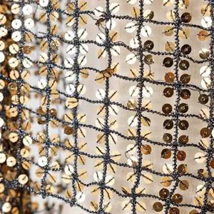 Close-up detail of black mesh fabric adorned with sparkling gold sequins for evening wear.