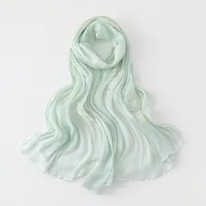 Close-up detail of mint green island silk scarf showing exquisite embroidery, lace and sequins.