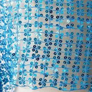 Blue sequin mesh fabric detail close-up showing sparkling flower pattern and delicate openwork design.