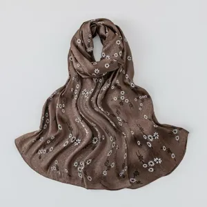 Detail shot of the brown floral imitation silk scarf showing delicate daisy print texture.