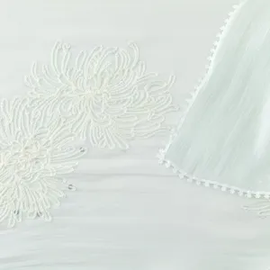 Close-up detail of mint green island silk scarf featuring delicate white floral embroidery.