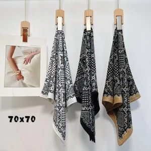 Detail view of vintage paisley print silk square scarves hanging on wooden clips for women.