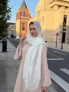 Outdoor street detail view of a lightweight white crinkled hijab and stylish pink dress.