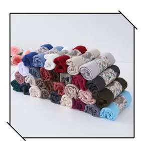 Stacked colorful bubble scarves rolled up neatly with floral band wraps, ideal for sun protection.
