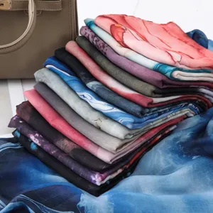 Detail view of colorful watercolor printed gradient women silk scarves neatly stacked.