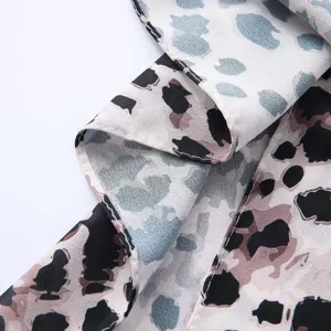 Detailed view of the watercolor tie-dye leopard print satin scarf fabric texture and stitching.