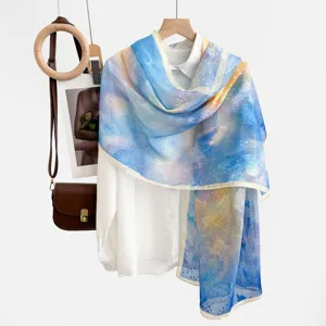 Detail view of a blue yellow gradient cutout sheer sun protection shawl scarf hanging nicely.