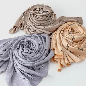 Detailed view of soft floral print scarves rolled neatly in three lovely colors, elegant style.