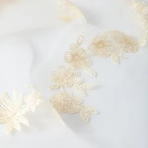 Close-up detail of delicate vintage beige floral lace embroidery on soft sheer fabric.