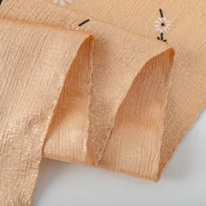 Detailed view of camel imitation silk fabric with delicate small flower print, soft texture.