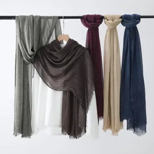 Vue détaillée de foulards uni en coton et lin accrochés proprement dans de superbes couleurs.