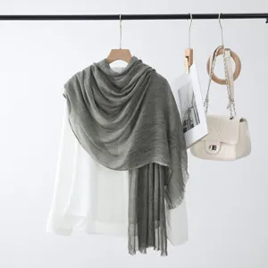 Vue rapprochée d'une écharpe en lin et coton vert-gris sur chemise blanche en présentation.