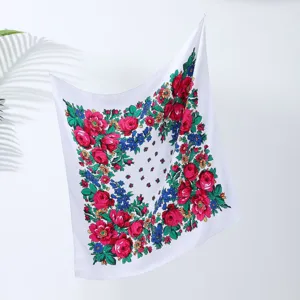 Close-up detail of retro floral square scarf with vibrant red roses and green leaves design.