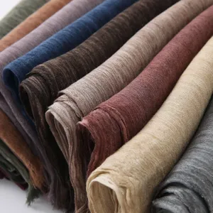 Gros plan détaillé de foulards roulés en coton et lin unis montrant une texture fine et des couleurs.