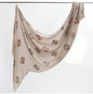 Close up detail of soft cotton linen scarf featuring elegant floral print and fringe edges.