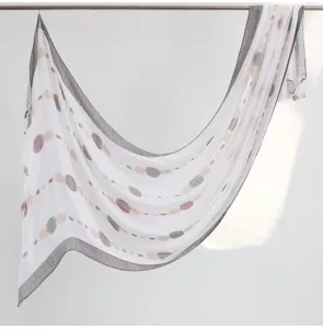 Close-up detail of the white cotton linen scarf featuring colorful dotted patterns and fringed edges.