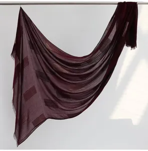 Burgundy textured cut-work scarf detail showcasing soft drape and delicate tassel edges.
