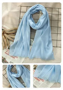 Light blue cotton linen scarf detail view, showing soft fabric texture and delicate frayed edges clearly.