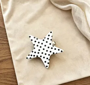 Detailopname van de witte stervormige haarspeld met een klassiek zwart stippenpatroon.