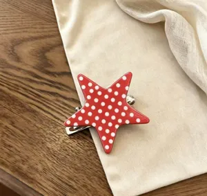 Detailopname van de rood-witte sterhaarklem met stippen, een leuk haaraccessoire.