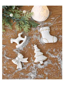Primo piano di eleganti decorazioni natalizie in ceramica bianca su un piano di legno.